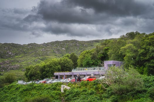 Killarney, Ireland, August 2019 People watching trough coin operated telescope beautiful Ladies View with car park and restaurant in the background