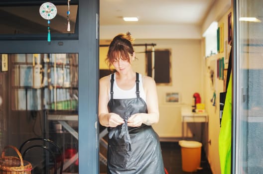 portrait of professional pet hairdresser hipster woman with tattoos while standing at the door of her beauty salon for animals