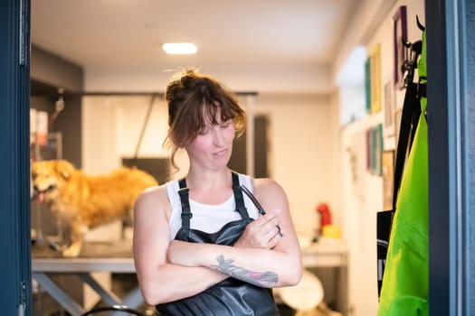 portrait of professional pet hairdresser hipster woman with tattoos while standing at the door of her beauty salon for animals