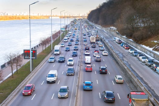 KYIV, UKRAINE - MARCH 03, 2021: Traffic on embankment road at sunset. Kyiv is the capital of Ukraine
