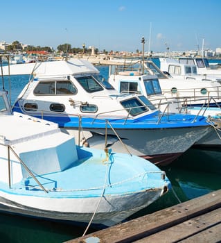 Motorboats in marina of Larnaca in bright sunshine, city embankment in background, Cyprus
