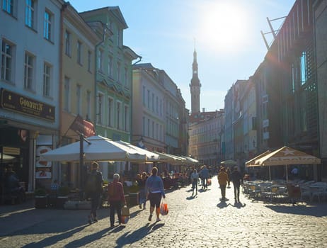TALLINN, ESTONIA - JULY 14, 2019: People walking by sunny street at Old Town of Tallinn.