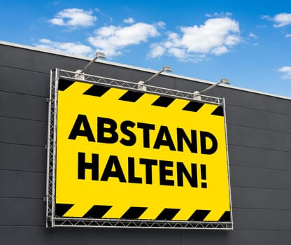 Keep distance in german written on a billboard - Abstand halten