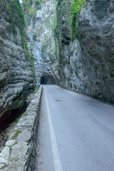 narrow mountain road under steep ravine at Brasa gorge, shot in bright fall light at Tremosine, Brescia, Italy.