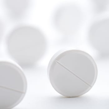 A pile of white pills scattered on a bright white background. Selective focus. Mockup layout, template.