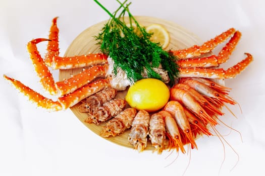 Red king crab and shrimp on a plate with lemon and dill. White background