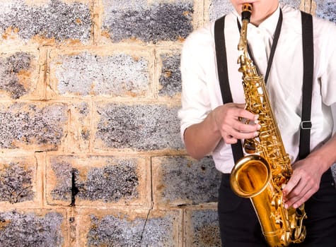 The  young man in a white shirt with sax on brick wall background