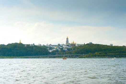 View of Kyiv-Pechersk lavra. Yacht on the Dnipro river. Kyiv, Ukraine