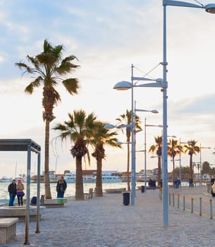 PAPHOS, CYPRUS - FEBRUARY 15, 2019: People walking by embankment at beautiful twilight in Paphos