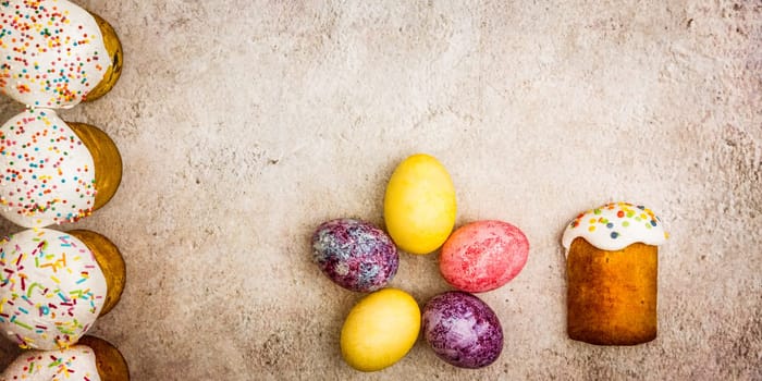 Easter cakes and Easter colored eggs on a beautiful textured background. Religious holiday of bright Easter.