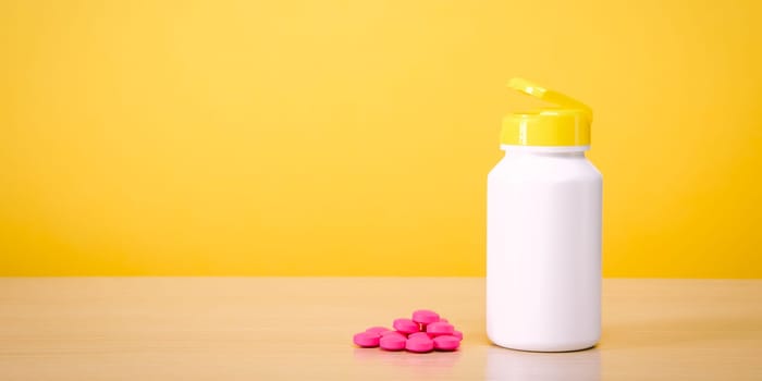 A white jar with scattered red pills on a yellow background. Place for the label, logo, layout.