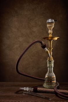Egyptian hookah (shisha) on dark brown table on dark background.