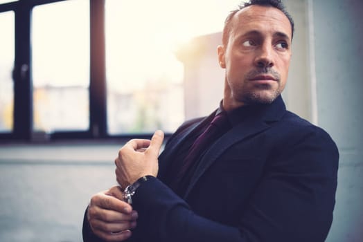 Pensive senior businessman against the window in a modern office