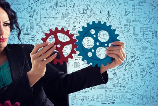 Businesswoman tries to connect gears pieces. Concept of Teamwork, partnership and business integration