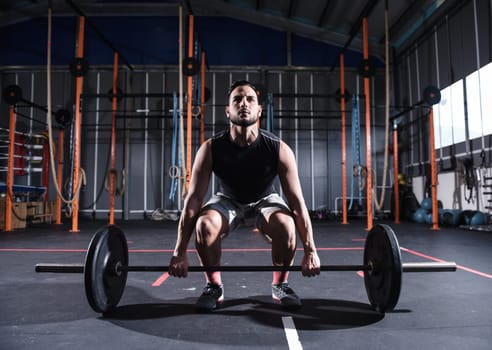 Determined athletic man works out at the gym with a barbell