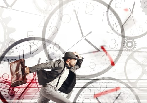 Business man runs fast on a background of clocks