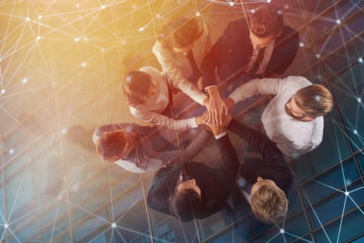 Business people putting their hands together in office with internet network effects. Concept of integration, teamwork and partnership. double exposure