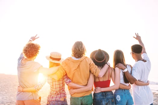 Group of happy friends having fun at ocean beach at dawn