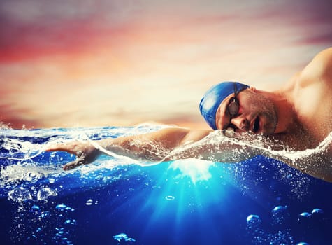 Boy swims in a blue deep water during sunset