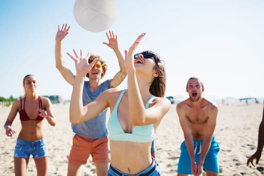 Group of happy friends playing at beach volley at the beach