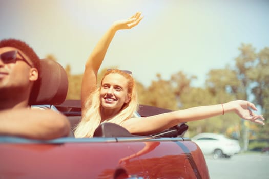 Young Caucasian woman in cabriolet car near sea departs for the summer holidays