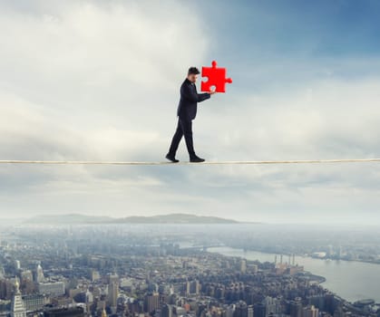 Businessman carries a piece of puzzle while he walking on a long rope. concept of missing piece