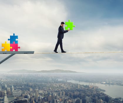 Businessman carries a piece of puzzle while he walking on a long rope. concept of missing piece