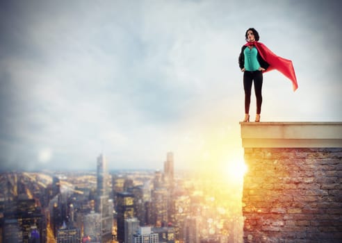 Successful businesswoman acts like a super hero above the roof of a building during sunrise. Concept of determination and success