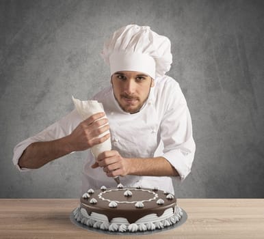 Pastry cook prepares a chocolate and cream cake
