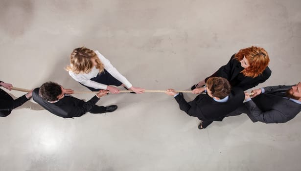 Rival business man and woman compete in office for the command by pulling the rope