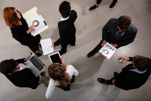 Team of people works together on company statistics in office. Shooted from above. Concept of teamwork and partnership