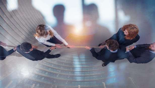 Rival business man and woman compete in office for the command by pulling the rope. double exposure