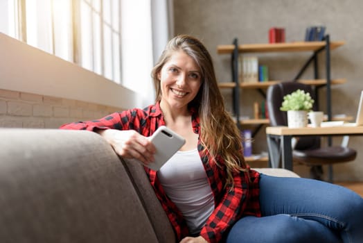 Girl relaxing on a sofa with her smartphone