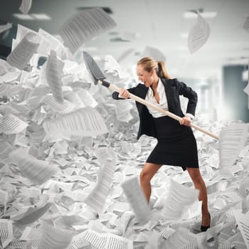 Business woman with shovel in office to get rid of paperwork