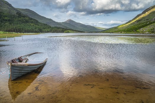 Sunken or half submerged paddle boat in Lough Gummeenduff with view on beautiful Black Valley, MacGillycuddys Reeks mountains, Ring of Kerry, Ireland