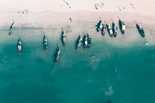 Aerial, drone view of a beautiful tropical beach with white sand, turquoise clear water and longtail boats near Krabi, Thailand.
