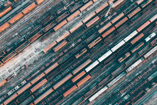 Aerial view of various railway carriage trains with goods on the railway station, top view.