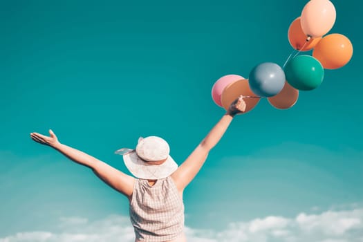 Young woman with colorful balloons in summer field - retro styled photo