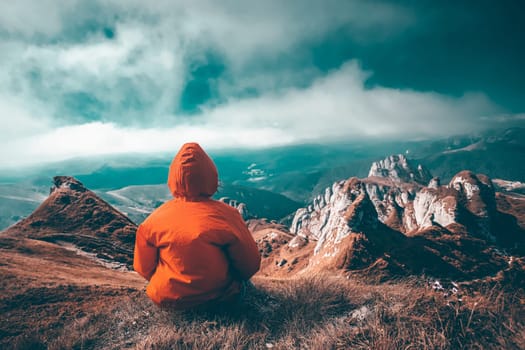 Woman sitting on cliff enjoying mountains landscape. Lifestyle concept. Traveling active adventure vacations.