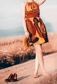 Closeup of happy young woman wearing light summer dress with flowers on sunny day outdoors