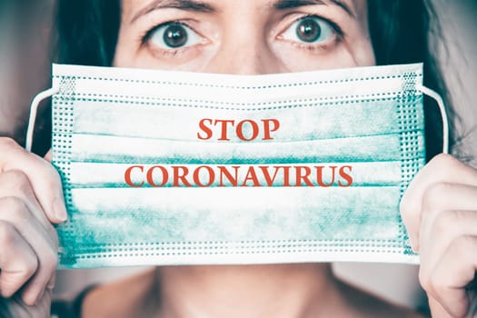 Woman wearing medical protective surgical face mask with text Stop coronavirus. Concept of protection against Covid-19, coronavirus outbreak campaign.