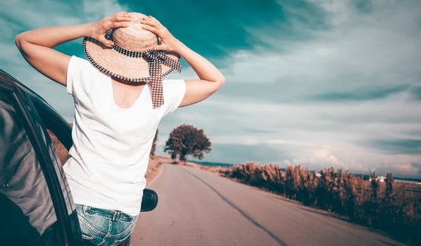 Young woman traveling in a car across Europe. Freedom, travel and vacation road trip concept lifestyle image.