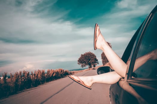 Woman's legs out of car windows.Freedom, travel and vacation road trip concept lifestyle image.