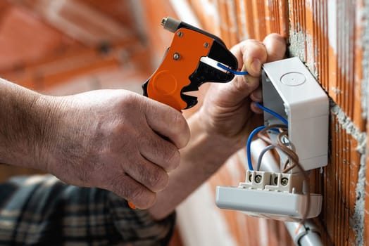 Bottom view. Electrician worker at work with wire stripper prepares the electrical cables of an electrical system. Construction industry.
