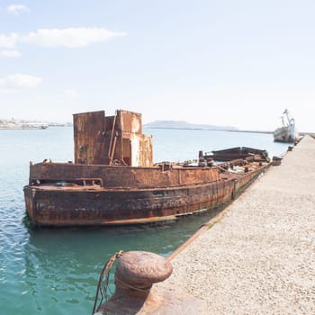 Rusty wreck moored, abandoned in the pier in the harbor of Cagliari Sardinia.