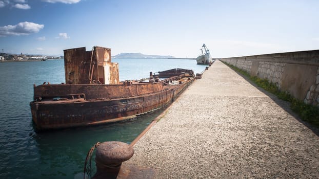 Rusty wreck moored, abandoned in the pier in the harbor of Cagliari Sardinia.