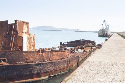 Rusty wreck moored, abandoned in the pier in the harbor of Cagliari Sardinia.