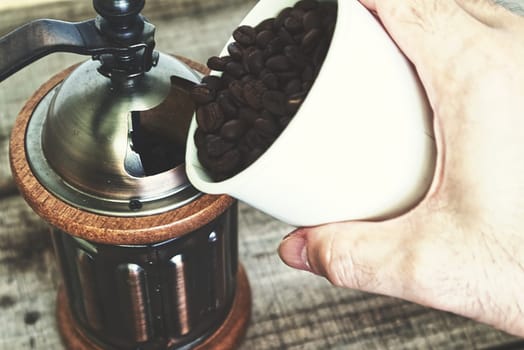 .Hand poured coffee beans on a coffee grinder.