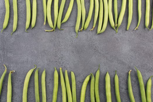 Green string beans on a textured background, empty space for text, fresh vegetables