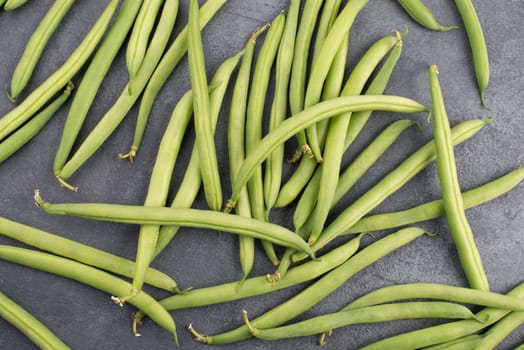 Green string beans on a textured background, empty space for text, fresh vegetables
